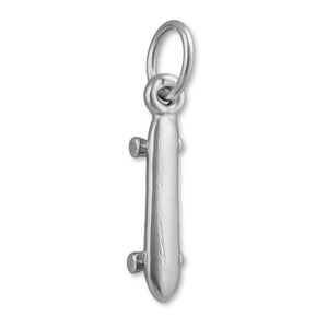 May include: A silver skateboard charm with a loop for attaching to a necklace or bracelet. The charm has a detailed design, including the wheels and the board's shape. The charm is made of a shiny, reflective metal.