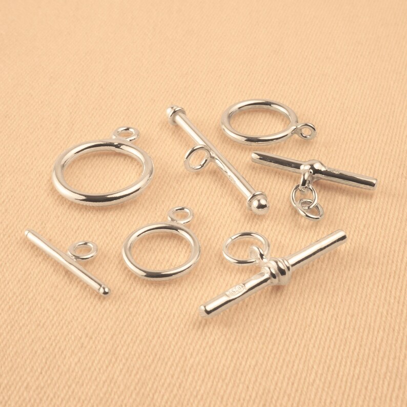 May include: Silver tone metal toggle clasps and rings for jewelry making. The clasps are in various styles, including a T-bar, a bar with a ball end, and a bar with a twisted design.