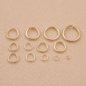 May include: Assortment of gold jump rings in various sizes. The jump rings are arranged in rows from largest to smallest.