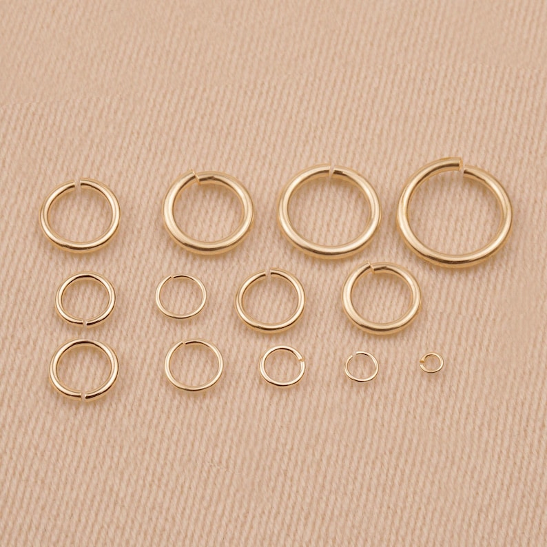 May include: Assortment of gold jump rings in various sizes. The jump rings are arranged in rows from largest to smallest.