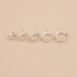 May include: A set of five silver-toned metal oval ring settings arranged in a row from smallest to largest. Each setting features a smooth oval base with four vertical prongs extending upward, designed to hold a gemstone securely in place.