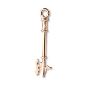 May include: A rose gold key pendant with a detailed design. The key has a loop at the top, a ribbed section, a long stem, and a decorative key bit. The pendant is likely for jewelry making or as a charm.
