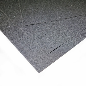 Peut inclure: Gros plan sur une feuille de papier de verre noir avec une surface rugueuse et texturée.