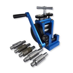 May include: A blue metal rolling mill machine featuring a hand crank with a black handle, a top adjustment T-handle, and exposed black gears. Five interchangeable steel rollers with varying smooth and grooved textures are arranged in front.
