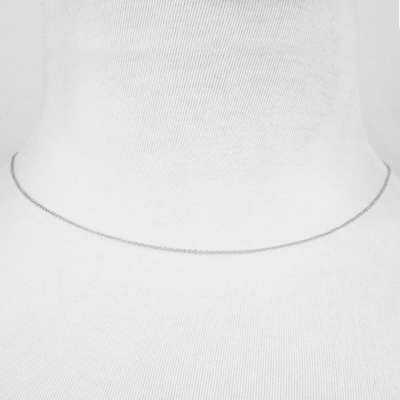 May include: A silver chain necklace on a white mannequin.