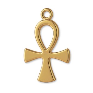 Puede incluir: Un colgante ankh de metal en tono dorado pulido con un diseño de cruz suave y redondeado, que incluye un lazo circular en la parte superior para su fijación. El dije tiene una superficie reflectante y una forma simétrica.
