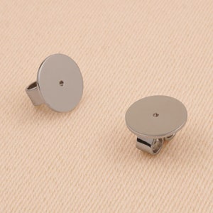 May include: Two silver earring backs with a round, flat surface and a small hole in the center. The backs are designed to be attached to the back of an earring post.