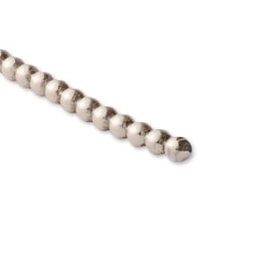 Könnte beinhalten: Eine silberne Perlenkette mit glatter, abgerundeter Oberfläche. Die Kette besteht aus kleinen, gleichmäßig verteilten Perlen.