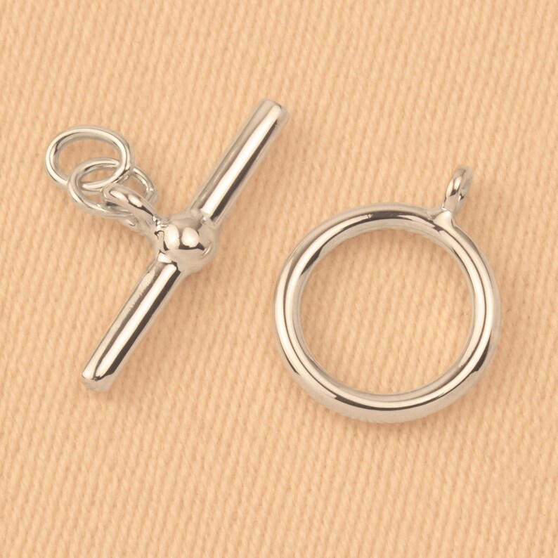 May include: Silver-toned toggle clasp with a round ring. The clasp is made of metal and has a polished finish.
