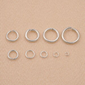 May include: Assortment of silver jump rings in various sizes. The jump rings are arranged in a row from largest to smallest.