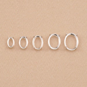 May include: Five silver-toned oval-shaped jewelry settings arranged in a horizontal row from smallest to largest. Each setting features four small prongs designed to hold a gemstone securely in place within the open metal frame.