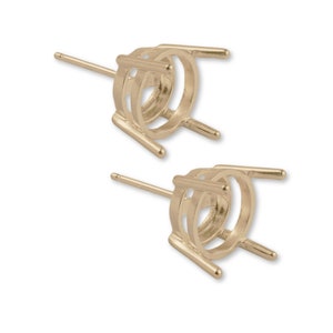 May include: A pair of gold-tone earring settings with prongs for holding gemstones. The settings are round and have a post for attaching to an earring back.