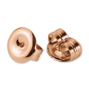 May include: Two rose gold earring backs. One back is a flat disc with a small hole in the center. The other back is a curved, open-back design with a small hole in the center.