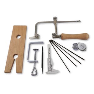 May include: A jewellery making kit with a saw, a wooden sawing board, a magnifying glass, a clamp, a ruler, a set of saw blades, and a small tool.