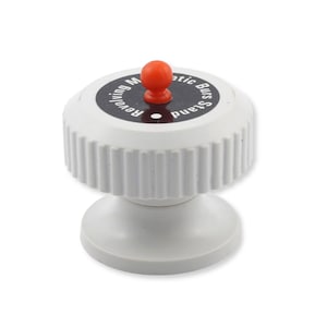 May include: A white revolving magnetic burs stand with a ribbed cylindrical top and a smooth flared base. The top features a black circular label with white text that reads Revolving Magnetic Burs Stand and a small orange spherical knob in the centre.
