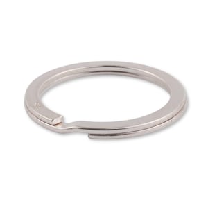 May include: A silver key ring with a split ring opening. The ring is made of metal and has a smooth, polished finish.