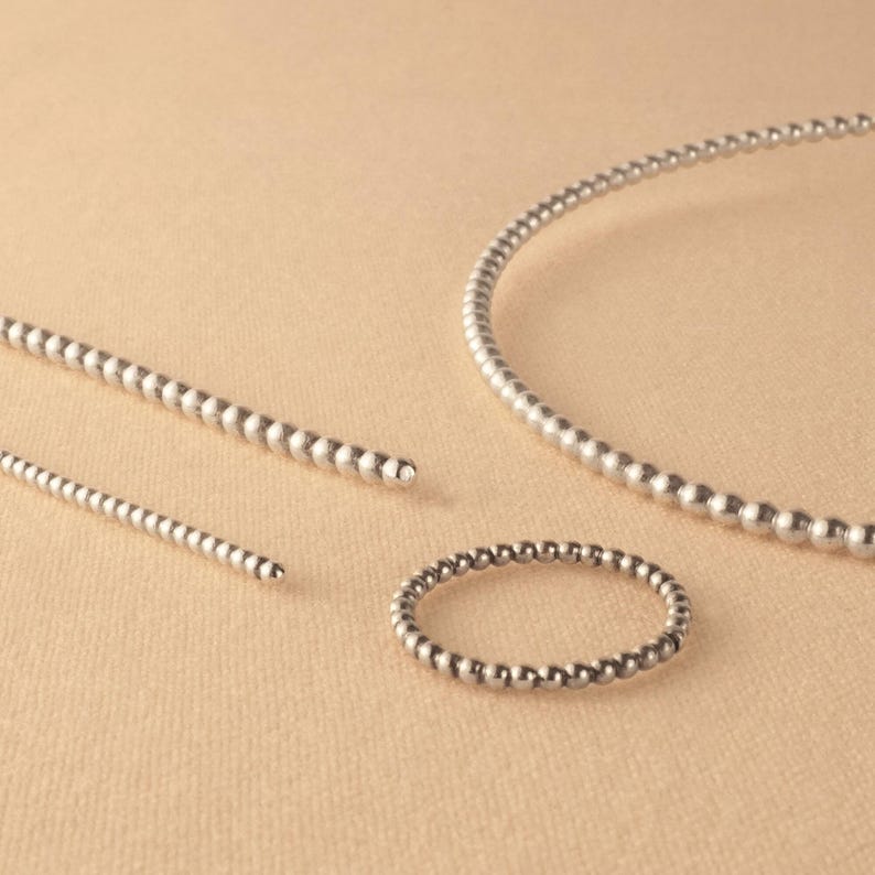 May include: Three silver beaded necklaces of varying lengths. The necklaces are made of small, round beads that are evenly spaced.