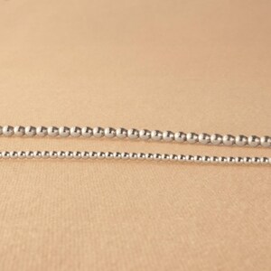 May include: Two silver bead necklaces of different sizes. The larger necklace has larger beads and the smaller necklace has smaller beads.