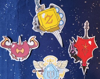 May include: Four colorful stickers featuring different designs. The first sticker is a yellow and gold shield with a sword and a Z symbol. The second sticker is a red and black shield with a sword and a diamond symbol. The third sticker is a blue and white shield with a sword and a T symbol. The fourth sticker is a red and white crab with a yellow symbol.