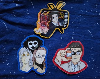 Pode incluir: Três adesivos em estilo anime em um fundo azul. Um adesivo apresenta uma pessoa em uma tela de TV, outro mostra três personagens e o último mostra uma pessoa segurando um pote com o rótulo "Hemocra".