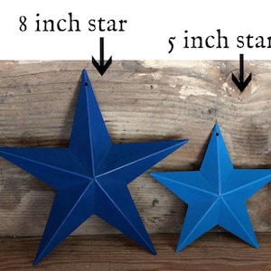 May include: Two blue metal stars, one 8 inches and one 5 inches, on a wooden background.