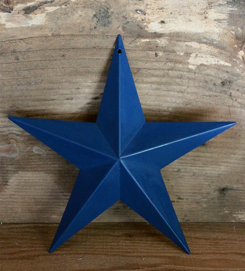 May include: A large, five-pointed star made of metal painted in a deep blue color. The star has a hole in the top for hanging.
