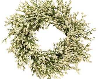 May include: A white and green artificial floral wreath with small white flowers and green leaves.