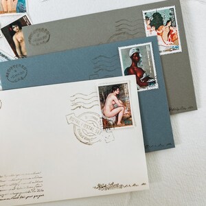 May include: A white envelope with a blue envelope and a gray envelope on top. The envelopes have stamps with images of people. The white envelope has a stamp with a woman sitting down and a stamp with a woman standing up. The blue envelope has a stamp with a woman standing up. The gray envelope has a stamp with a woman standing up and a stamp with a woman sitting down. The envelopes have a stamp that says "Royal Postal Set" and "United Kingdom".