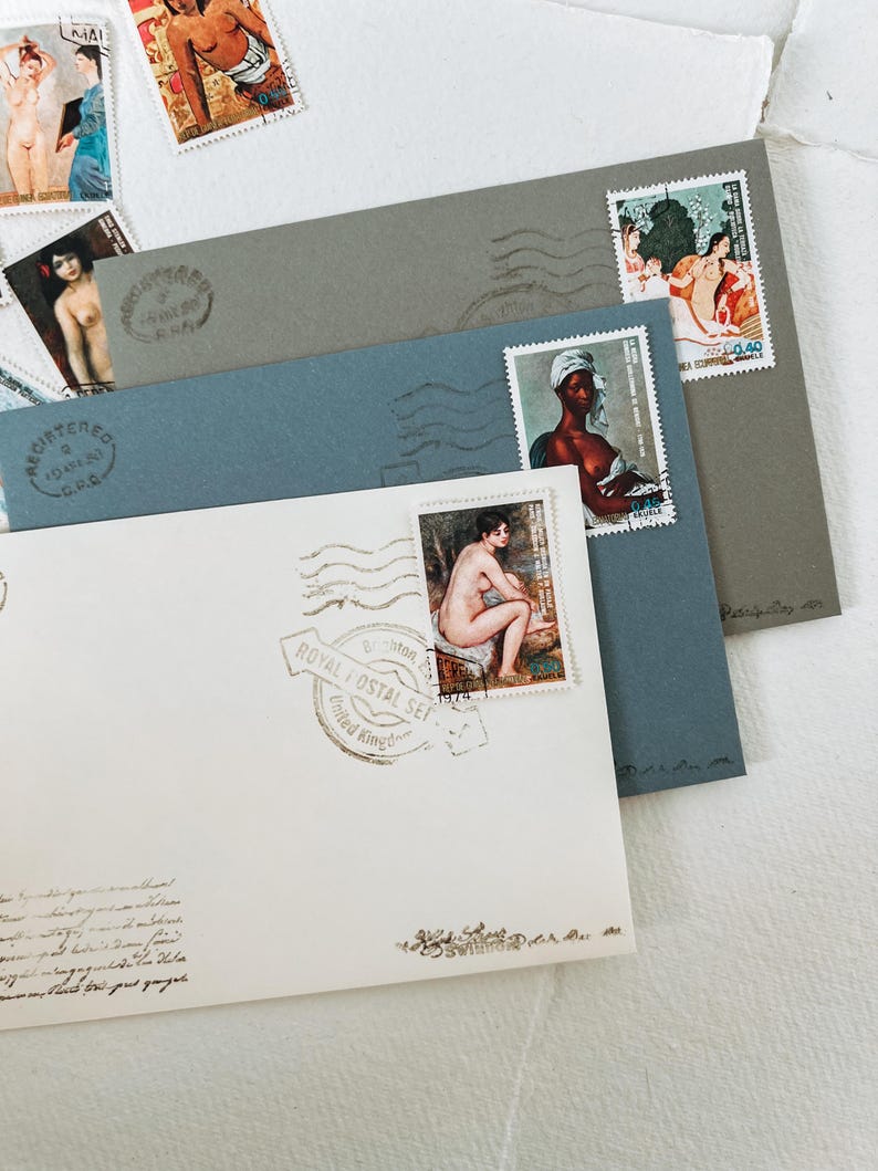 May include: A white envelope with a blue envelope and a gray envelope on top. The envelopes have stamps with images of people. The white envelope has a stamp with a woman sitting down and a stamp with a woman standing up. The blue envelope has a stamp with a woman standing up. The gray envelope has a stamp with a woman standing up and a stamp with a woman sitting down. The envelopes have a stamp that says "Royal Postal Set" and "United Kingdom".