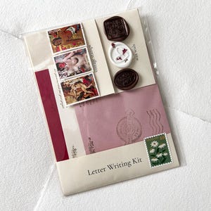 May include: A letter writing kit with a pink envelope, a white envelope, a red envelope, three wax seals, three vintage stamps, and a "Thank You" stamp with white daisies.