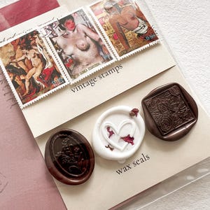 May include: A set of three wax seals, two brown and one white. The brown seals have floral designs and the white seal has a heart shape. The seals are displayed on a white card with the text "vintage stamps" and "wax seals".