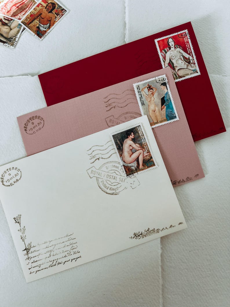 May include: Three envelopes with stamps featuring nude figures. The envelopes are layered, with a red envelope on top, a pink envelope in the middle, and a white envelope on the bottom. The stamps are from different countries and feature different nude figures. The white envelope has a stamp that says "Royal Postal Set, United Kingdom".