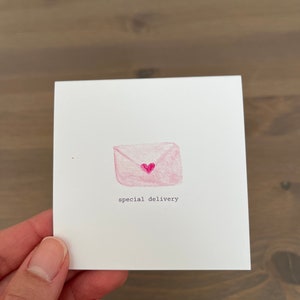 May include: A pink envelope with a small pink heart on the front. The text "special delivery" is written below the envelope.