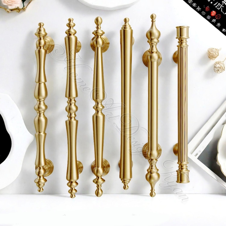 Puede incluir: Una colecci&oacute;n de seis manijas de puerta doradas con varios dise&ntilde;os ornamentados. Cada manija presenta una placa trasera decorativa para el montaje. Las manijas var&iacute;an en longitud y estilo, mostrando una gama de dise&ntilde;os elegantes de inspiraci&oacute;n vintage.