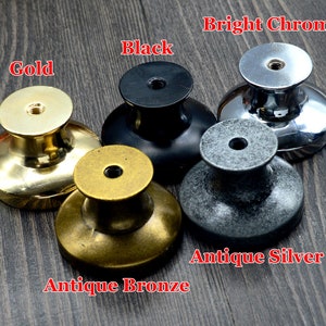 Pode incluir: Cinco bot&otilde;es de arm&aacute;rio em diferentes acabamentos: dourado, bronze antigo, preto, prata antiga e cromo brilhante. Os bot&otilde;es s&atilde;o redondos com um centro elevado e uma superf&iacute;cie lisa.