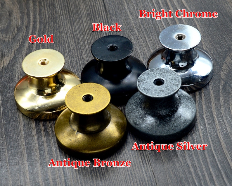 Pode incluir: Cinco bot&otilde;es de arm&aacute;rio em diferentes acabamentos: dourado, bronze antigo, preto, prata antiga e cromo brilhante. Os bot&otilde;es s&atilde;o redondos com um centro elevado e uma superf&iacute;cie lisa.