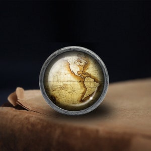 May include: A vintage-style globe with a silver metal frame and a detailed map of the world. The globe is sitting on a brown surface.