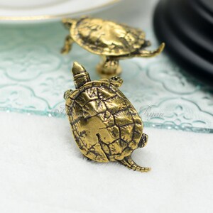May include: Two gold-toned turtle drawer pulls with a detailed, textured shell design.