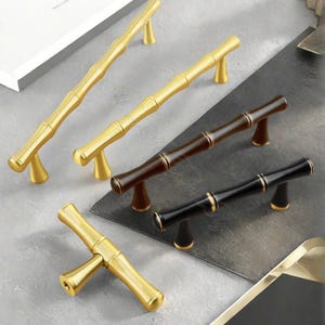 Puede incluir: Tiradores de armario con diseño de bambú, en acabados dorado, marrón oscuro y negro. Los tiradores están diseñados para parecer tallos de bambú, con detalles dorados. Añaden un toque natural y elegante a los muebles.