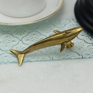 May include: A gold whale-shaped cabinet knob or drawer pull. The whale is facing right and has a detailed design.