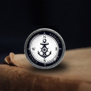 May include: A silver compass with a black anchor and the words "Smooth Sailing Since 1839" around the edge.