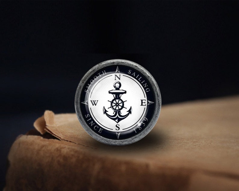 May include: A silver compass with a black anchor and the words "Smooth Sailing Since 1839" around the edge.