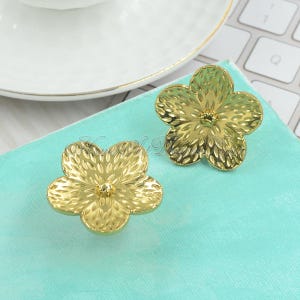 May include: Two gold-colored flower-shaped drawer pulls with a textured surface.