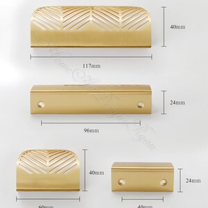 K&ouml;nnte beinhalten: Eine Sammlung goldfarbener Schrankgriffe. Der gr&ouml;&szlig;te Griff ist 117 mm lang und 40 mm hoch, mit einem dekorativen blattartigen Muster. Weitere Griffe sind 96 mm und 40 mm lang, und 40 mm lang und 24 mm hoch.