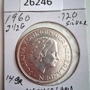 May include: A silver coin from the Netherlands, dated 1960, with the text "JULIANA KONINGIN DER NEDERLANDEN". The coin is marked as .720 silver and weighs 14.9 grams. The word "NETHERLAND" is written at the bottom.