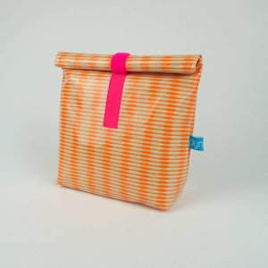 Pode incluir: Bolsa de almoço listrada laranja e branca com um puxador de zíper rosa e um rótulo azul "byn".