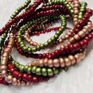 May include: A close-up of a multi-strand beaded bracelet with red, green, and gold beads.