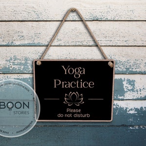 Könnte beinhalten: Schwarzes Holzschild mit weißem Text, der "Yoga Practice" lautet, und einer rosa Lotusblütengrafik. Das Schild hat auch den Text "Please do not disturb" in weiß.