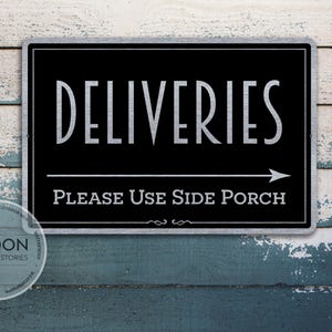 Könnte beinhalten: Ein rechteckiges schwarzes Schild mit silberner Schrift, das „DELIVERIES“ über „PLEASE USE SIDE PORCH“ mit einem Pfeil nach rechts zeigt. Das Schild befindet sich auf einem verwitterten, bemalten Holzgrund.
