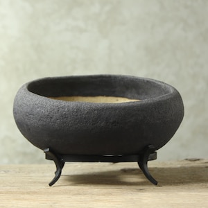 Oval black flower pot with stand. Size: 20 cm (width) 14-17 cm (height)